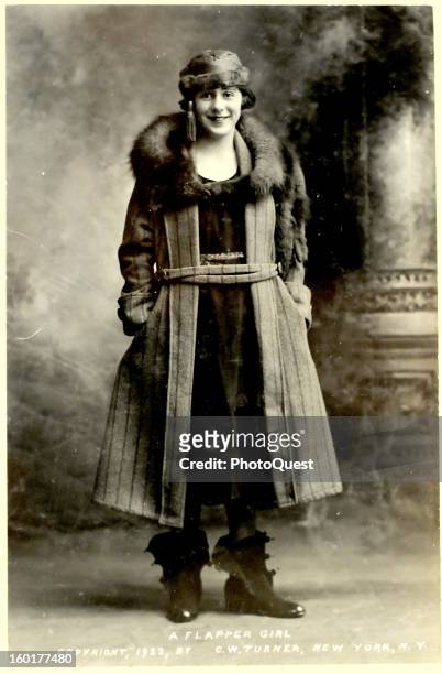 Portrait of an unidentified 'Flapper Girl' with in a fur-lined coat and hat, hands in her pockets, and a paior of unbuckled galoshes on her feet, May...