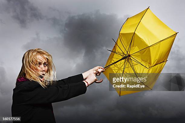 pretty woman is blown away: not in a good way - broken umbrella stockfoto's en -beelden