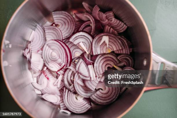 a close up view of red onion frying in a pan - onion family stock pictures, royalty-free photos & images