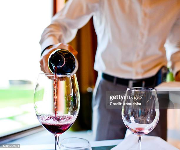 waiter pouring red wine in glass - sommelier stock pictures, royalty-free photos & images