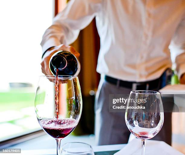 waiter pouring red wine in glass - luxury hotel service stock pictures, royalty-free photos & images