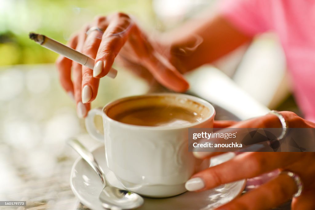 Donna bere caffè e fumo in caffè all'aperto