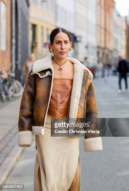 Idalia Salsamendi wears brown shearling jacket, beige skirt with slit, brown off shoulder top, necklace, heels during the Copenhagen Fashion Week...