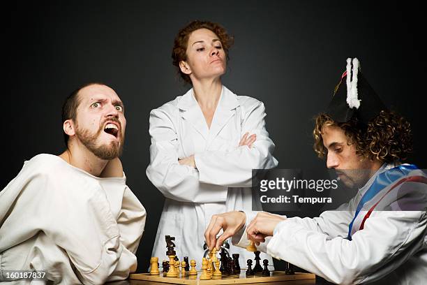 loony chess competition at the mental asylum in straightjacket. - straitjacket stock pictures, royalty-free photos & images