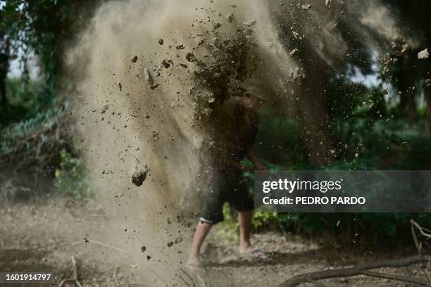 This picture taken on July 19, 2023 shows men throwing dirt in an attempt to prevent photos from being taken at a site where some graves were located...