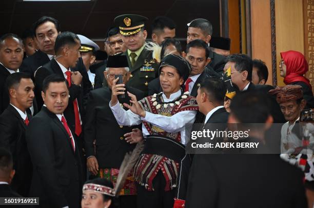 Indonesian President Joko Widodo takes a picture after attending the annual session of the People's Representative Council in Jakarta on August 16,...