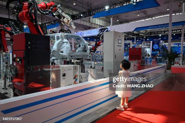 Child looks at a Siasun robot arm at the 2023 World Robot Conference in Beijing on August 16, 2023.