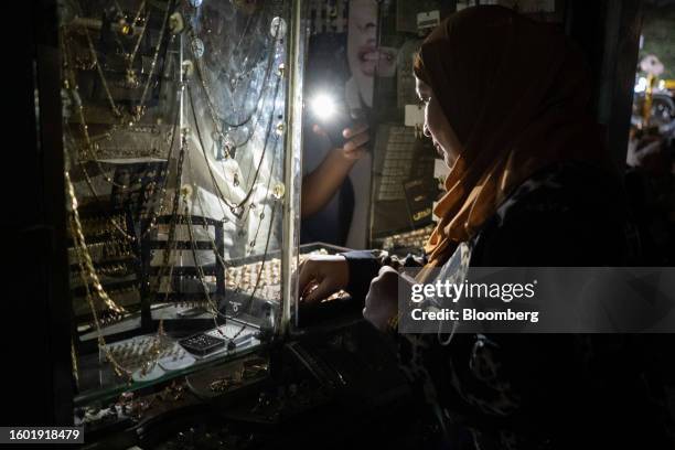 Customer browses costume jewelry by smartphone torch light in a store during a loadshedding power outage period, in the El-Sayeda Zainab district of...