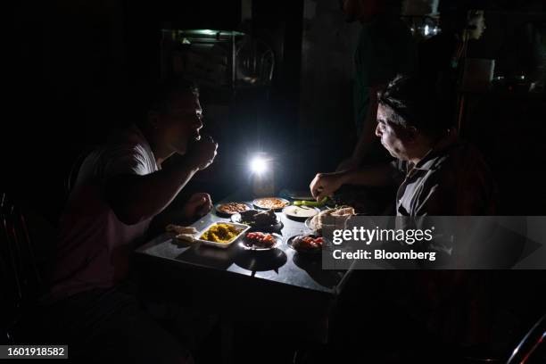 Customers eat by smartphone torch light inside an unlit restaurant during a loadshedding power outage period, in the Al-Muneera district of Cairo,...