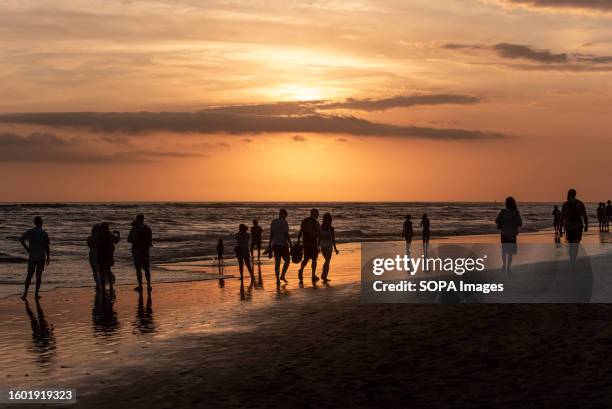 Tourists gather on Canggu Beach to watch the sunset. The beach is a popular spot for tourists and surfers.