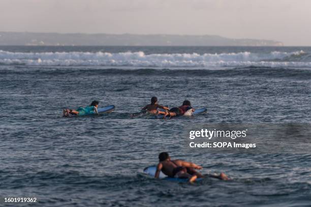 Group of surfers prepares to surf at Canggu Beach. The beach is a popular spot for tourists and surfers.