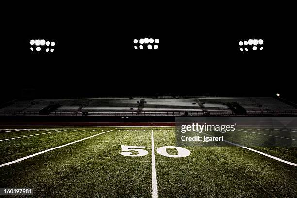 fifty-yard line of football field at night - american football speler stockfoto's en -beelden