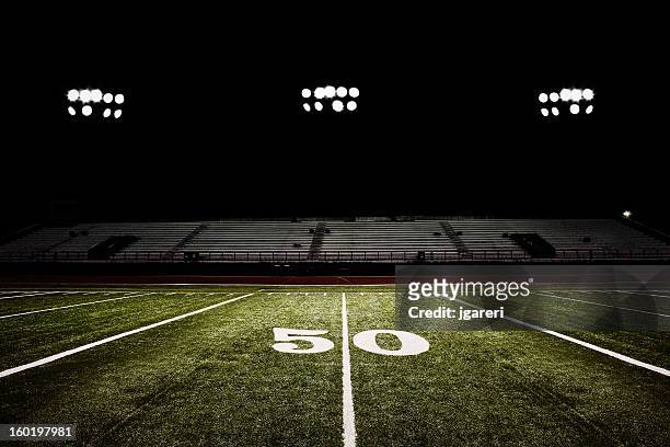 fifty-yard line of football field at night - american football field stock pictures, royalty-free photos & images