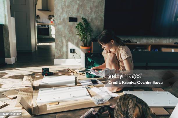 tired young woman sitting on the floor in front of furniture items, can not collect furniture - furniture instructions stock pictures, royalty-free photos & images