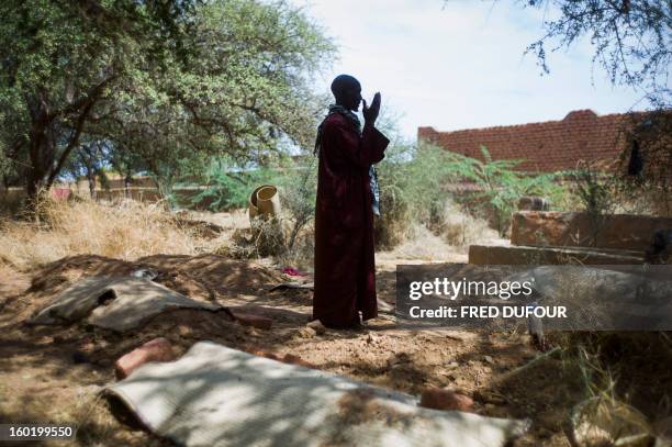 Laurence BOUTREUX - Idrissa Maiga, a Malian farmer, prays among the graves of his wife and three of his children in a cemetery behind the Konna...