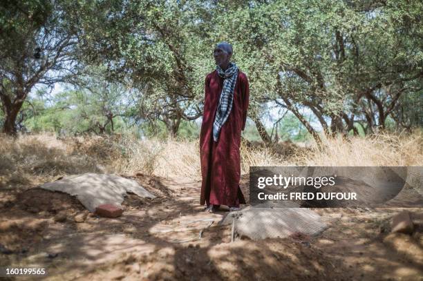 Laurence BOUTREUX - Idrissa Maiga, a Malian farmer, stands among the graves of his wife and three of his children in a cemetery behind the Konna...