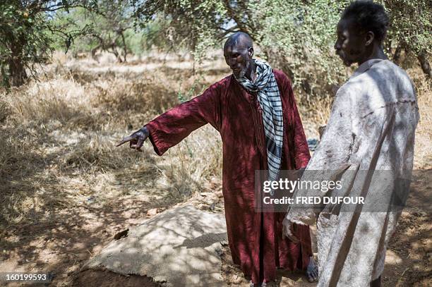 Laurence BOUTREUX - Idrissa Maiga , a Malian farmer, shows the graves of his wife and three of his children in a cemetery behind the Konna school on...