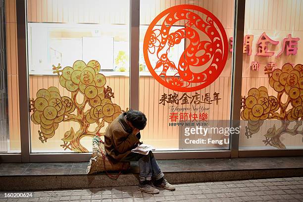 Poor man sits outside a department store on January 27, 2013 in Guiyang of Guizhou Province, China.