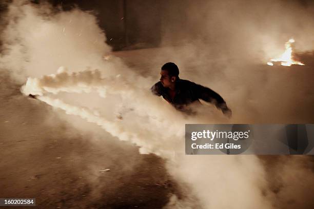 An Egyptian protester throws a live tear gas canister fired by riot police toward a fire during clashes near Tahrir Square on January 27, 2013 in...