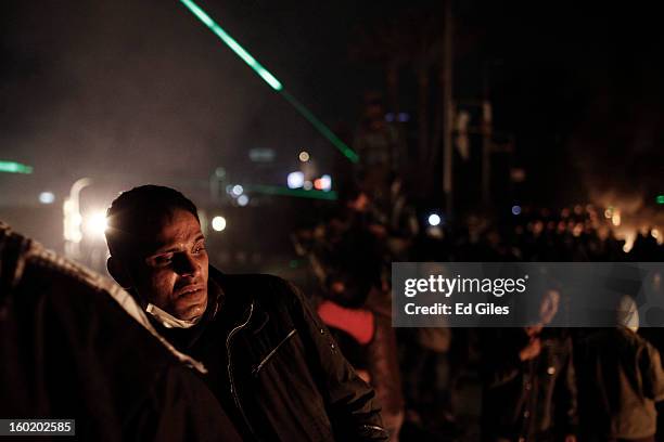 An Egyptian protester looks toward a nearby fire lit during clashes with riot police near Tahrir Square on January 27, 2013 in Cairo, Egypt. Violent...