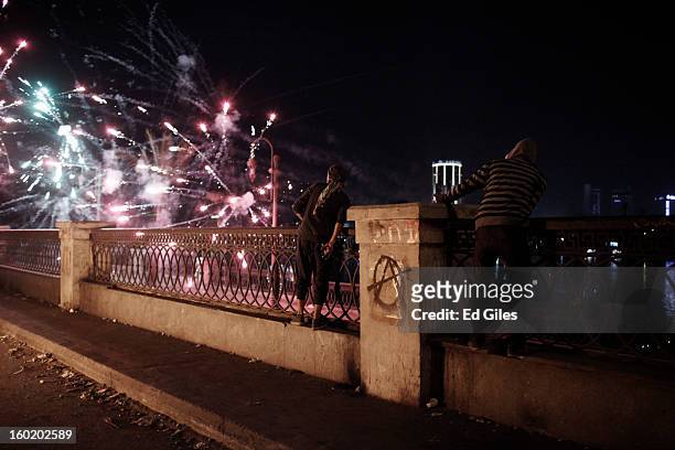 Egyptian protesters look on as fireworks shot toward nearby riot police explode during clashes near Tahrir Square on January 27, 2013 in Cairo,...