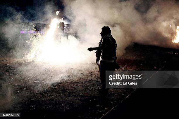 An Egyptian protester stands amongst smoke and tear gas during clashes with riot police near Tahrir Square on January 27, 2013 in Cairo, Egypt....