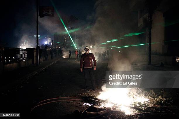 An Egyptian protester stands by a fire lit during clashes with riot police near Tahrir Square on January 27, 2013 in Cairo, Egypt. Violent protests...