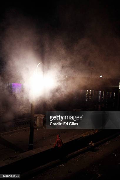 An Egyptian protester sits underneath a street lamp shrouded in tear gas during clashes with riot police near Tahrir Square on January 27, 2013 in...