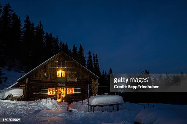 lightened mountain hut in the austrian alps - winter hut stock pictures, royalty-free photos & images
