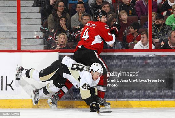 Joe Vitale of the Pittsburgh Penguins falls to the ice after checking Chris Phillips of the Ottawa Senators along the boards during an NHL game at...