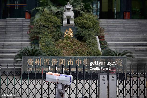 Man carrying a box walks outside Guiyang Intermediate People's Court before a press conference on former Chinese leader Bo Xilai's case on January...