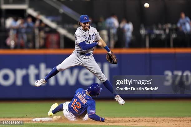 Dansby Swanson of the Chicago Cubs jumps over Francisco Lindor of the New York Mets as he turns a double play during the ninth inning to end the game...
