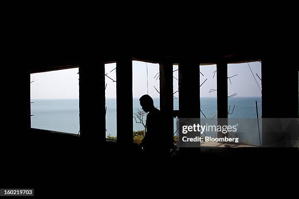 Man is silhouetted against a view of the ocean as he walks through a hotel under construction in Chaung Tha, Myanmar, on Saturday, Jan. 19, 2013....