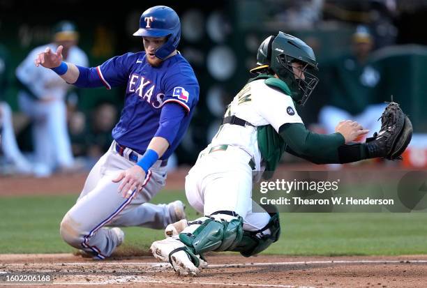 Sam Huff of the Texas Rangers scores sliding past Tyler Soderstrom of the Oakland Athletics in the top of the fourth inning at RingCentral Coliseum...