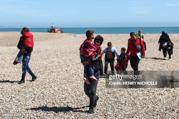 Man carries a child in his arms after disembarking from a Royal National Lifeboat Institution lifeboat, that picked them up at sea while crossing the...