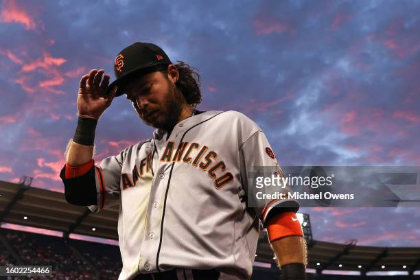 Brandon Crawford of the San Francisco Giants adjusts his hat as he walks into the dugout during the fourth inning of a game against the Los Angeles...