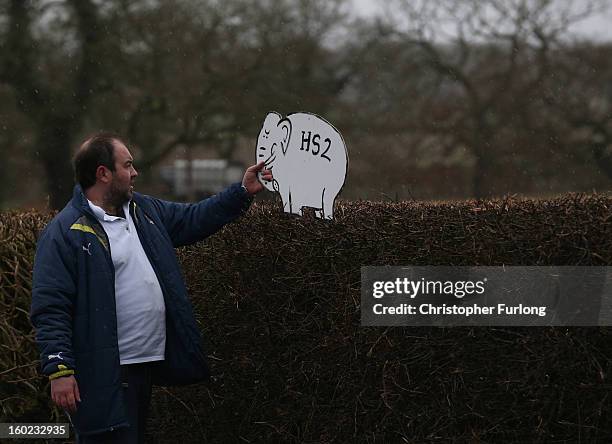 Joe Rukin from the Stop the HS2 Campaign places a cardboard white elephant in hedgerow near to the planned location of the new HS2 high speed rail...