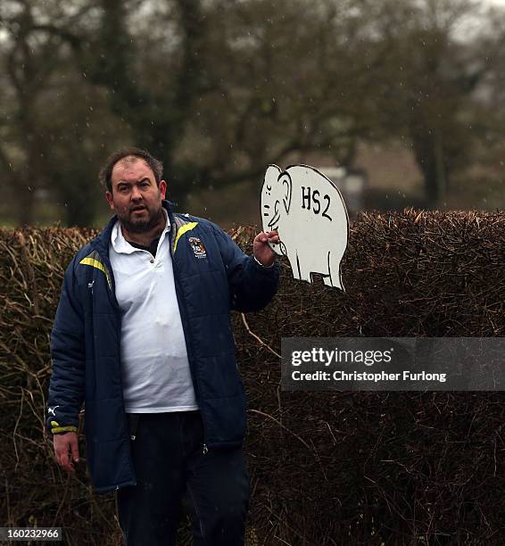 Joe Rukin from the Stop the HS2 Campaign places a cardboard white elephant in hedgerow near to the planned location of the new HS2 high speed rail...