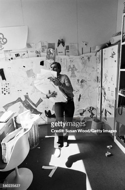 American fashion designer Betsey Johnson carries a pile of sketches in her studio, New York, New York, September 6, 1966.