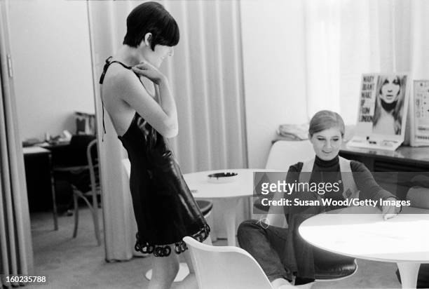 American fashion designer Betsey Johnson sits at a table in her studio and talks with an unidentified model, New York, New York, September 6, 1966.