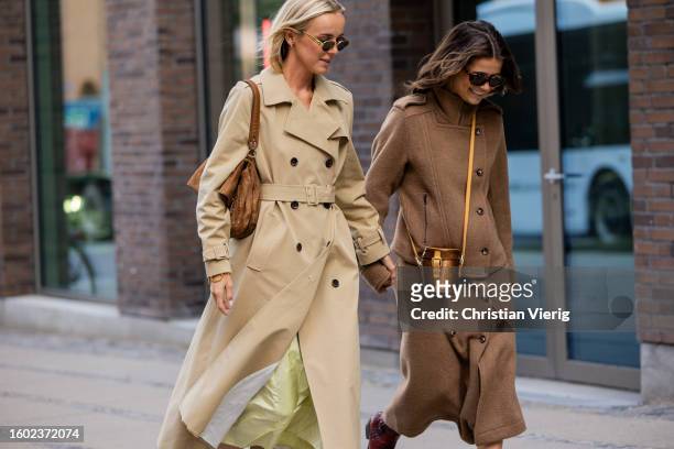 Guest wears beige trench coat, brown bag and a guest wears brown jacket, skirt, bucket bag outside Lovechild during the Copenhagen Fashion Week...