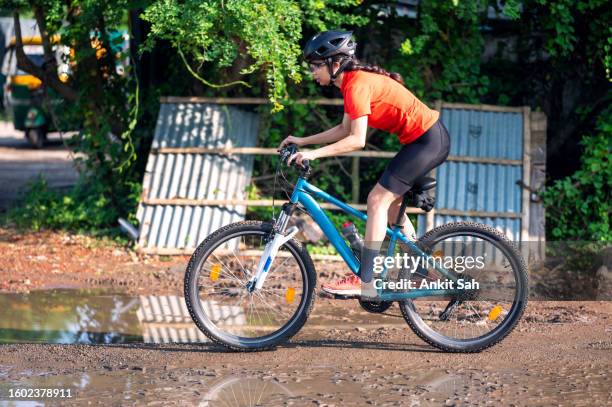 young sports cyclist riding her mountain bike on muddy trail on street - cycling event stock pictures, royalty-free photos & images