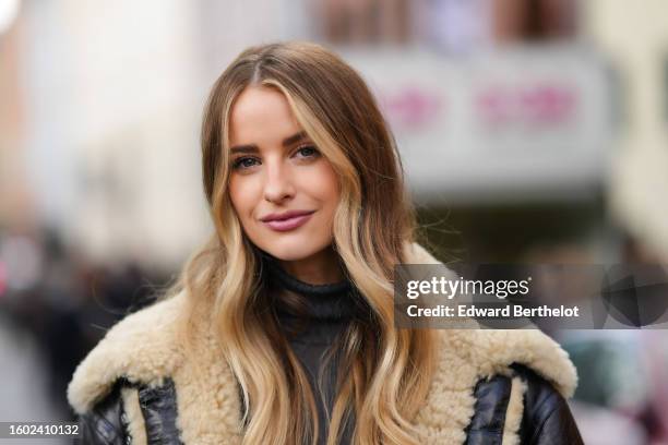 Victoria Magrath wears a dark gray ribbed wool turtleneck pullover, a black shiny leather with beige sheep fur details oversized aviator coat,...