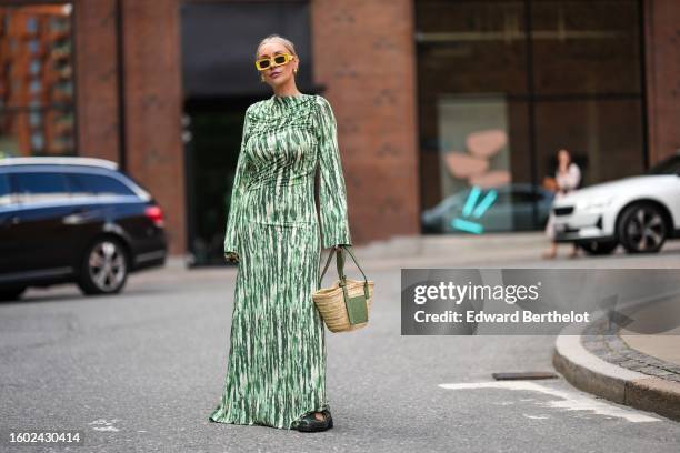 Justyna Czerniak wears yellow squared sunglasses from Loewe, gold earrings, a green and white latte marble print pattern high neck / long sleeves /...