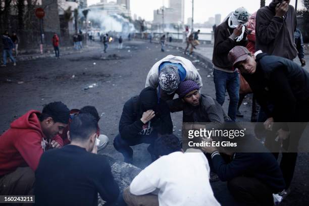 Group of Egyptian protester affected by exposure to tear gas gather beside a fire during clashes between protesters and Egyptian riot police near...