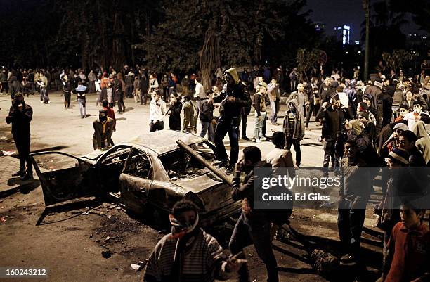 Egyptian protesters gather around the burnt-out wreck of a car during clashes between protesters and Egyptian riot police near Tahrir Square on...