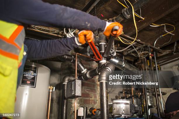 Plumbers install a new boiler in a basement at a private residence January 17, 2013 flooded during Hurricane Sandy in the Rockaways January 17, 2013...