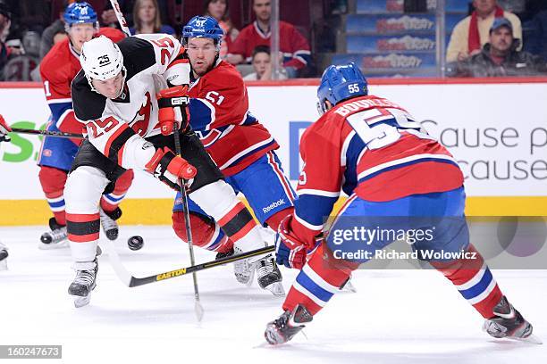 Cam Janssen of the New Jersey Devils attempts to move the puck past David Desharnais and Francis Bouillon of the Montreal Canadiens during the NHL...