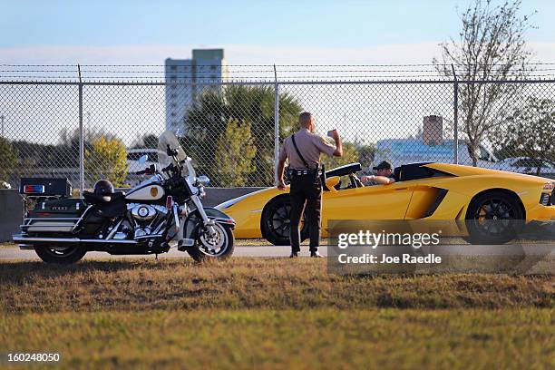 Miami-Dade police officer takes pictures of a new Lamborghini Aventador LP700-4 Roadster as it is seen at the Miami International Airporton January...