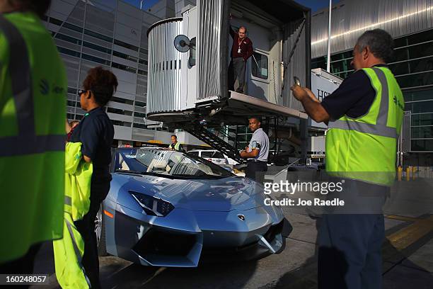 Airport workers look at the new Lamborghini Aventador LP700-4 Roadster on the tarmac at the Miami International Airporton January 28, 2013 in Miami,...